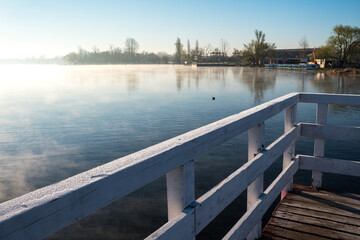 Jetty on a lake with fog. Wooden structure on the water. Sunrise and fog over the water.