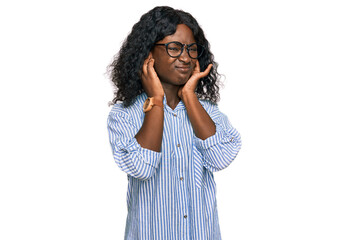 Beautiful african young woman wearing casual clothes and glasses covering ears with fingers with annoyed expression for the noise of loud music. deaf concept.