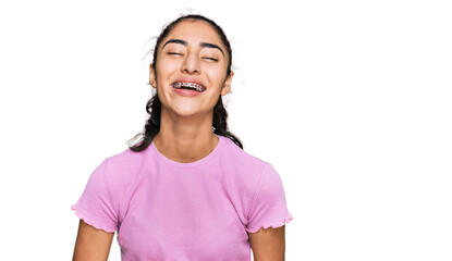 Hispanic teenager girl with dental braces wearing casual clothes smiling and laughing hard out loud because funny crazy joke with hands on body.