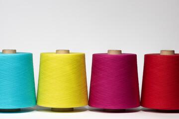 bobbins of multi-colored threads stand in a row on a white isolated background