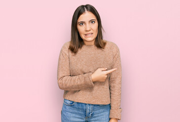 Young beautiful woman wearing casual clothes pointing aside worried and nervous with forefinger,...