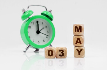 On a white background there is an alarm clock and a calendar with the inscription - MAY 03