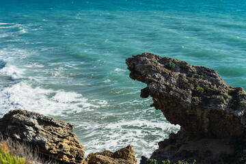 Piedra sobresaliendo de un acantilado con el mar de fondo