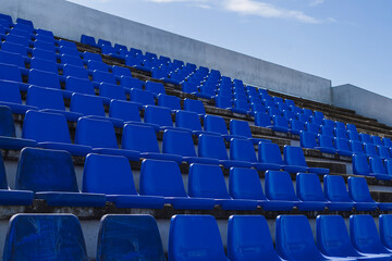 Gradas de estadio de futbol modesto con asientos de color azul