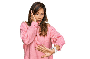 Young hispanic woman wearing casual clothes looking at the watch time worried, afraid of getting...