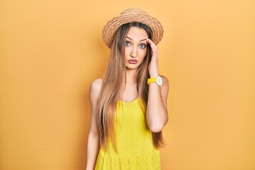 Young blonde girl wearing summer hat worried and stressed about a problem with hand on forehead, nervous and anxious for crisis