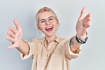 Beautiful caucasian woman with blond hair wearing casual look and glasses looking at the camera...