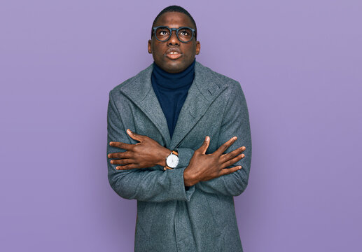 Young african american man wearing business clothes and glasses shaking and freezing for winter cold with sad and shock expression on face