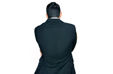 Handsome hispanic man wearing business clothes hugging oneself happy and positive from backwards....