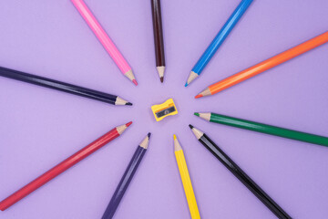 Naklejka premium Colored pencils for drawing and a sharpener on a lilac background.