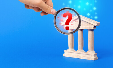 A hand with a magnifying glass inspects bank and finds financial violations. Audit and accounting....