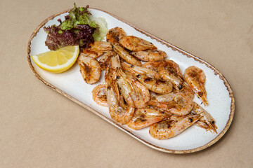 Fried shrimps on a platter with lemon and salad.