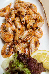 Fried shrimps on a platter with lemon and salad.
