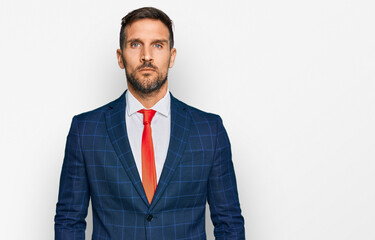 Handsome man with beard wearing business suit and tie relaxed with serious expression on face. simple and natural looking at the camera.