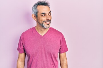 Obraz premium Handsome middle age man with grey hair wearing casual pink t shirt looking to side, relax profile pose with natural face and confident smile.