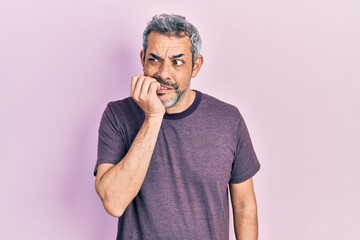 Handsome middle age man with grey hair wearing casual t shirt looking stressed and nervous with...