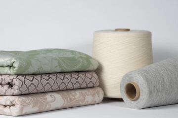 Spools with light thread and cotton cloth on a white isolated background. Textile and yarn industry concept