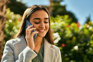 Young hispanic girl smiling happy talking on the smartphone at the city.