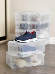 Footwear in plastic boxes on floor. Storage organization