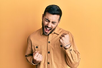 Young hispanic man wearing casual clothes celebrating surprised and amazed for success with arms raised and eyes closed