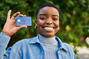 Young african american woman smiling happy holding credit card at the city.
