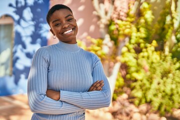 Young african american woman smiling happy with crossed arms at the city.