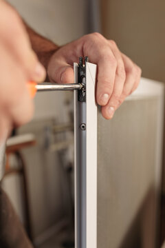 Man hand with screwdriver tool to assemble an aluminum window screen. Selective focus. Vertical image.