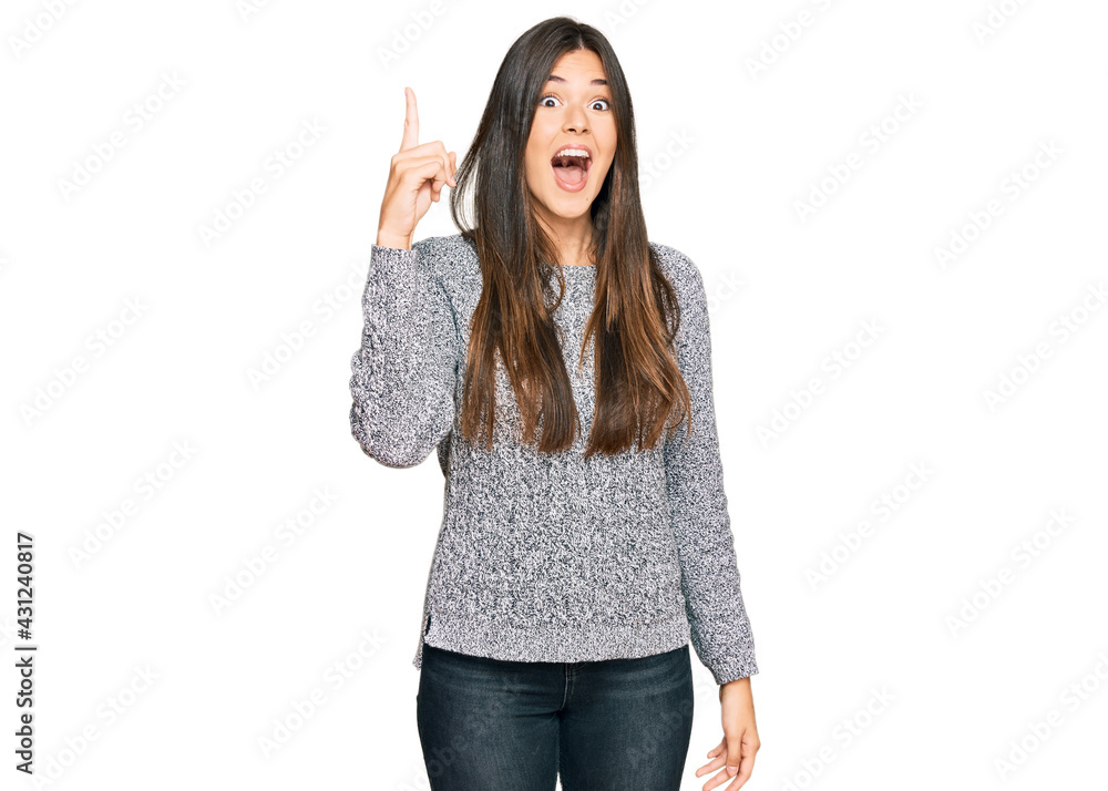 Sticker young brunette woman wearing casual winter sweater pointing finger up with successful idea. exited a