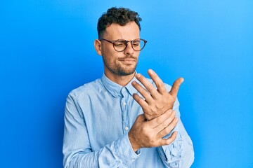Young hispanic man wearing casual clothes and glasses suffering pain on hands and fingers, arthritis inflammation