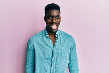 Handsome black man wearing casual clothes sticking tongue out happy with funny expression. emotion concept.