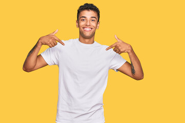 Young handsome african american man wearing casual white tshirt looking confident with smile on face, pointing oneself with fingers proud and happy. - Powered by Adobe