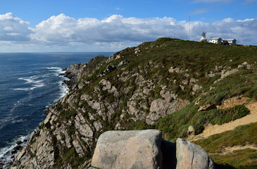 lighthouse on a rocky cliff above the cloudy sea