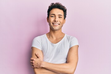 Young handsome man wearing casual white t shirt happy face smiling with crossed arms looking at the...