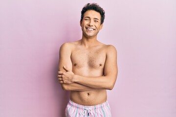 Fototapeta premium Young handsome man wearing swimwear shirtless happy face smiling with crossed arms looking at the camera. positive person.