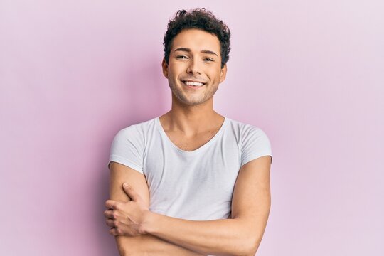 Young handsome man wearing casual white t shirt happy face smiling with crossed arms looking at the camera. positive person.