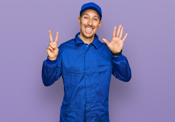 Fototapeta premium Bald man with beard wearing builder jumpsuit uniform showing and pointing up with fingers number seven while smiling confident and happy.