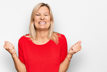 Middle age caucasian woman wearing casual clothes very happy and excited doing winner gesture with arms raised, smiling and screaming for success. celebration concept.