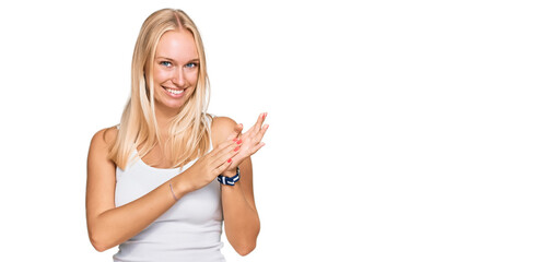 Young blonde girl wearing casual style with sleeveless shirt clapping and applauding happy and...