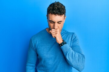 Hispanic young man wearing casual winter sweater feeling unwell and coughing as symptom for cold or bronchitis. health care concept.