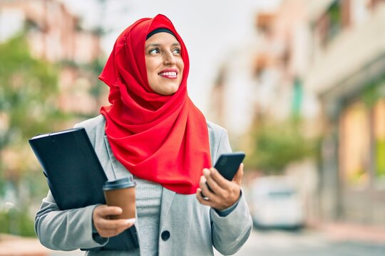 Young arab businesswoman using smartphone and drinking coffee at the city.