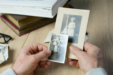 closeup male hand holding old vintage photos of 1940-1950, concept of family tree, genealogy,...
