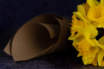 A partially visible bouquet of Narcissuses is lying beside a paper cone