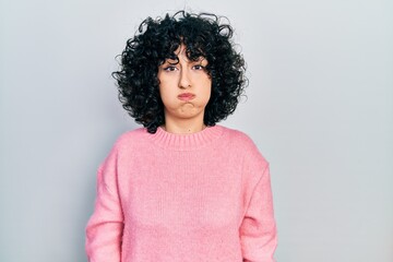 Young middle east woman wearing casual clothes puffing cheeks with funny face. mouth inflated with...