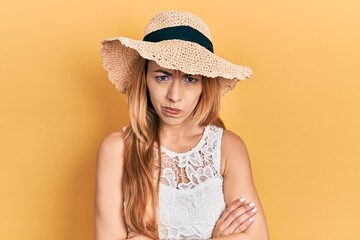 Young caucasian woman wearing summer hat skeptic and nervous, disapproving expression on face with...