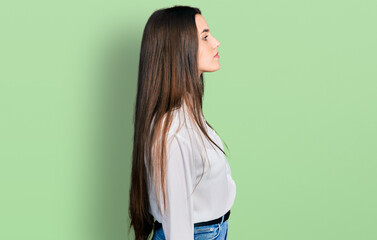 Young brunette teenager wearing business white shirt looking to side, relax profile pose with...