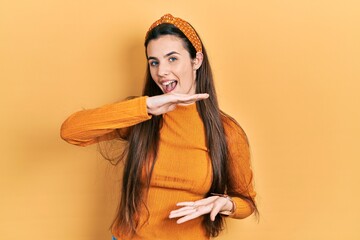 Young brunette teenager wearing casual yellow sweater gesturing with hands showing big and large size sign, measure symbol. smiling looking at the camera. measuring concept.