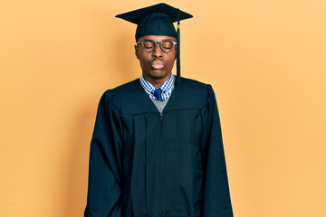 Young african american man wearing graduation cap and ceremony robe looking at the camera blowing a kiss on air being lovely and sexy. love expression.