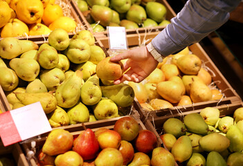 man buying pears and apples in a supermarket