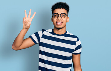 Fototapeta premium Young african american man wearing casual clothes and glasses showing and pointing up with fingers number three while smiling confident and happy.