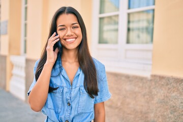 Young latin girl smiling happy talking on the smartphone at the city.